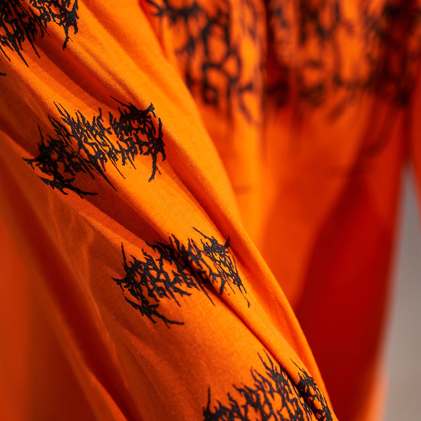 Orange long-sleeve T-shirt featuring a Barbed Wire Architects print across the front and along the sleeves