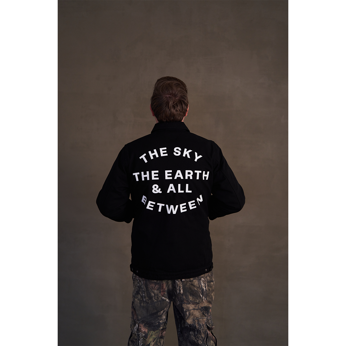 Black canvas jacket featuring white Architects text print on the front right chest and The Sky, the Earth and All Between text print across the back.