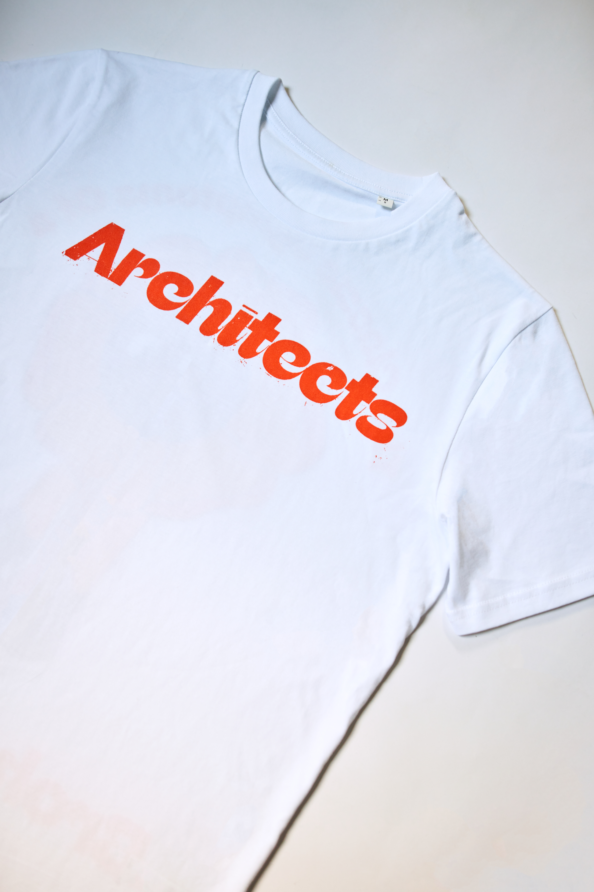 White short-sleeve unisex t-shirt with 
a red Architects logo print across the front