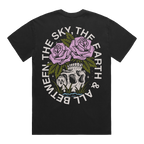 Back of a black short-sleeve t-shirt featuring a flower–skull graphic, with white text around it that reads “The Sky, The Earth & All Between.”