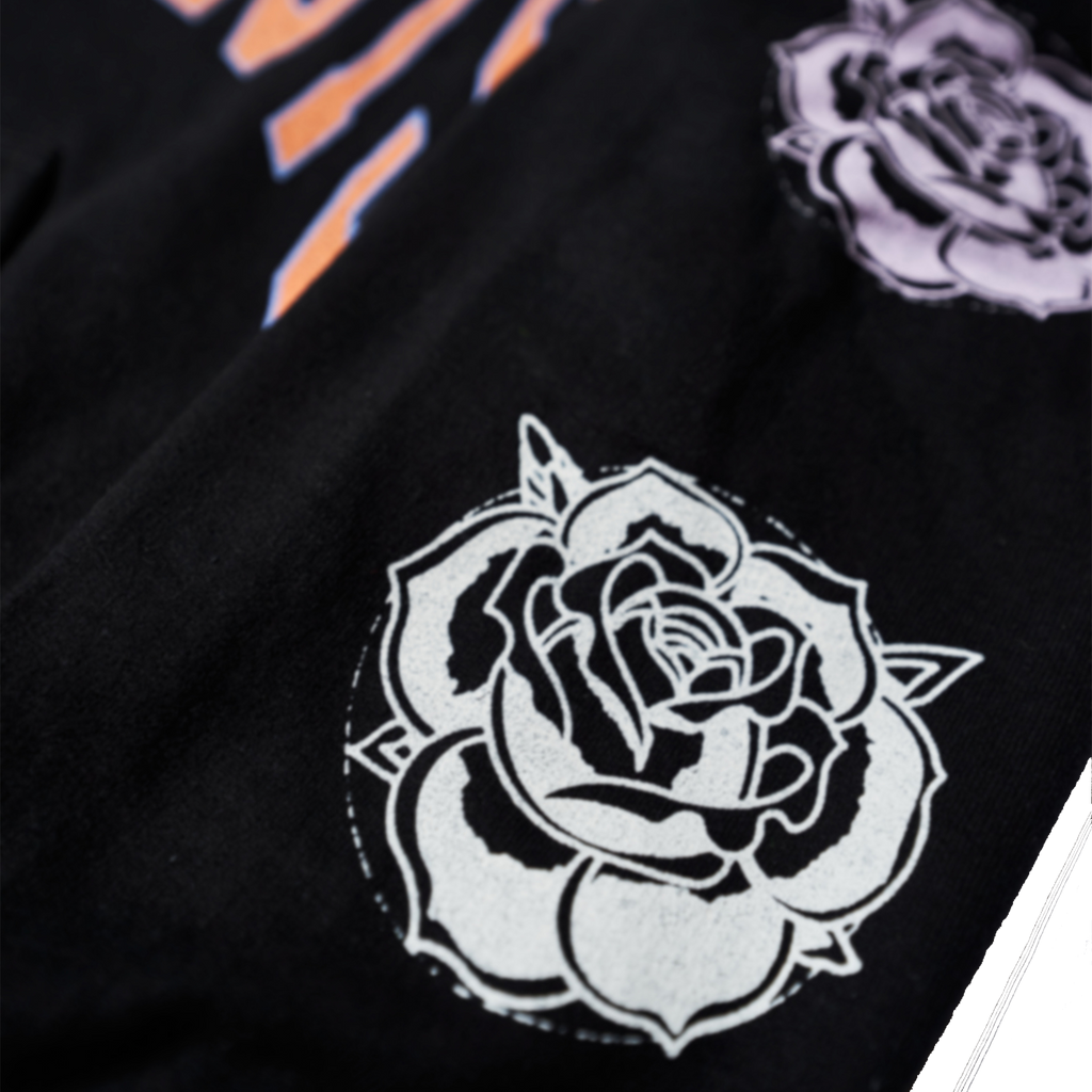 Black regular-fit unisex hoodie featuring an orange Architects print across the front, with blue, pink, and white rose prints along the sleeves.