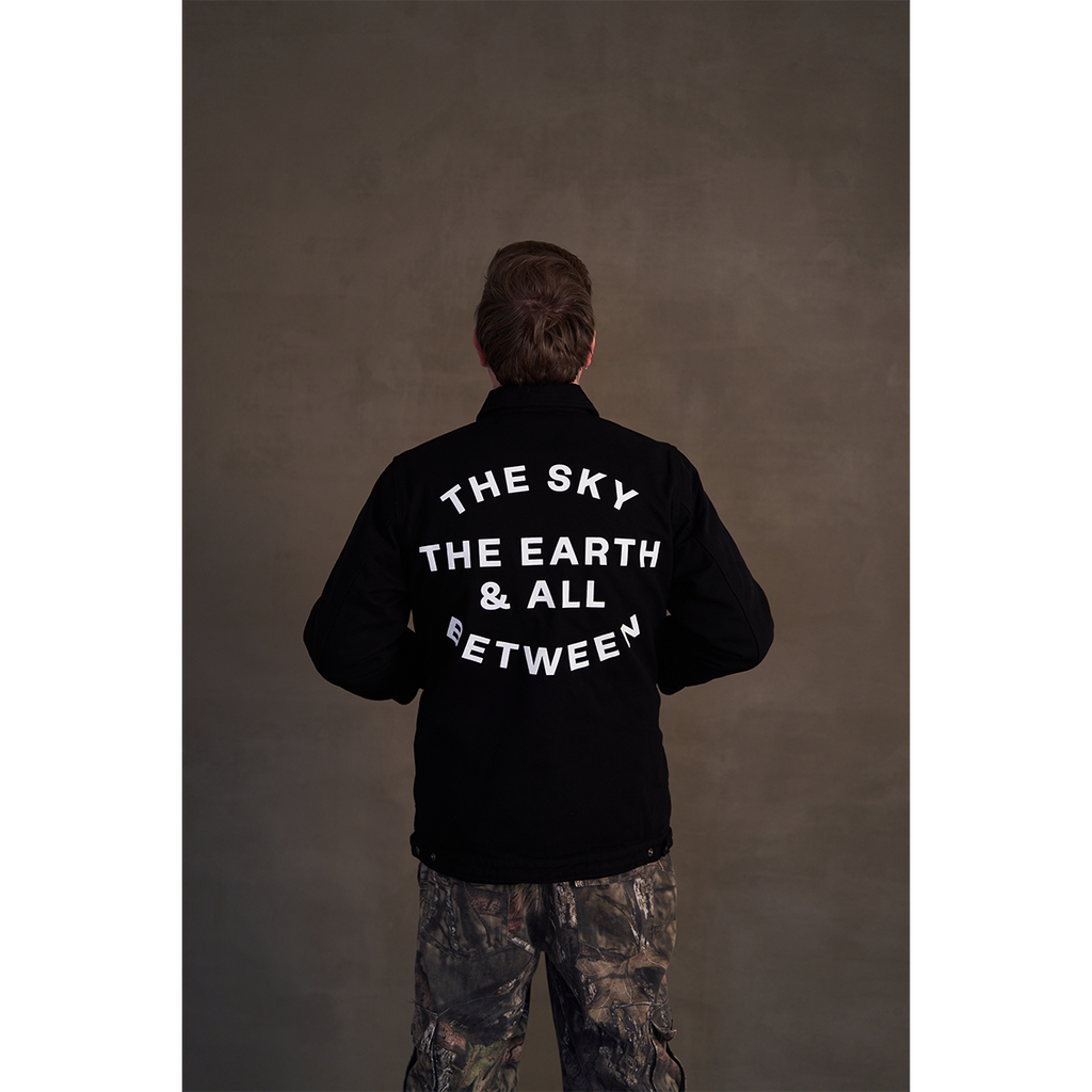 Black canvas jacket featuring white Architects text print on the front right chest and The Sky, the Earth and All Between text print across the back.
