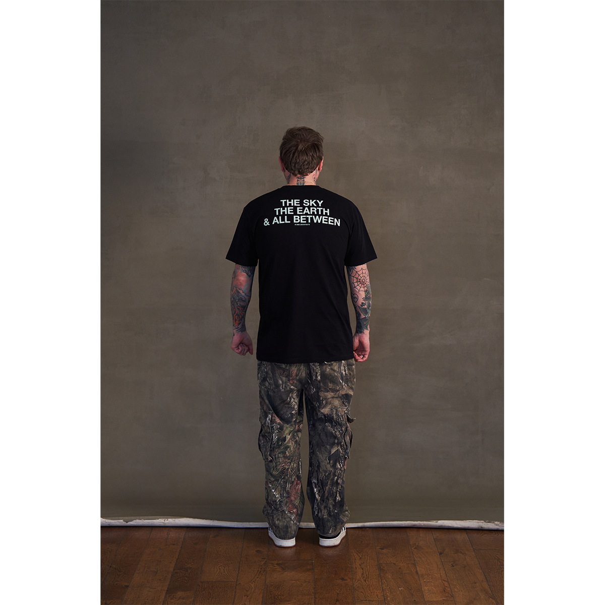 Black short-sleeve unisex regular fit T-shirt featuring the Architects Glow print across the front and The Sky, the Earth & All Between text print across the back.