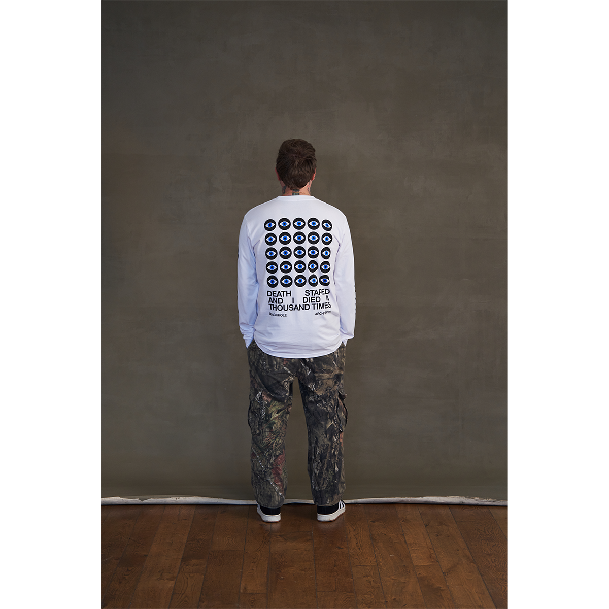White long-sleeve unisex regular fit T-shirt with Architects Blackhole eye print across the back, Architects text along the right sleeve, and eye print along the left sleeve.